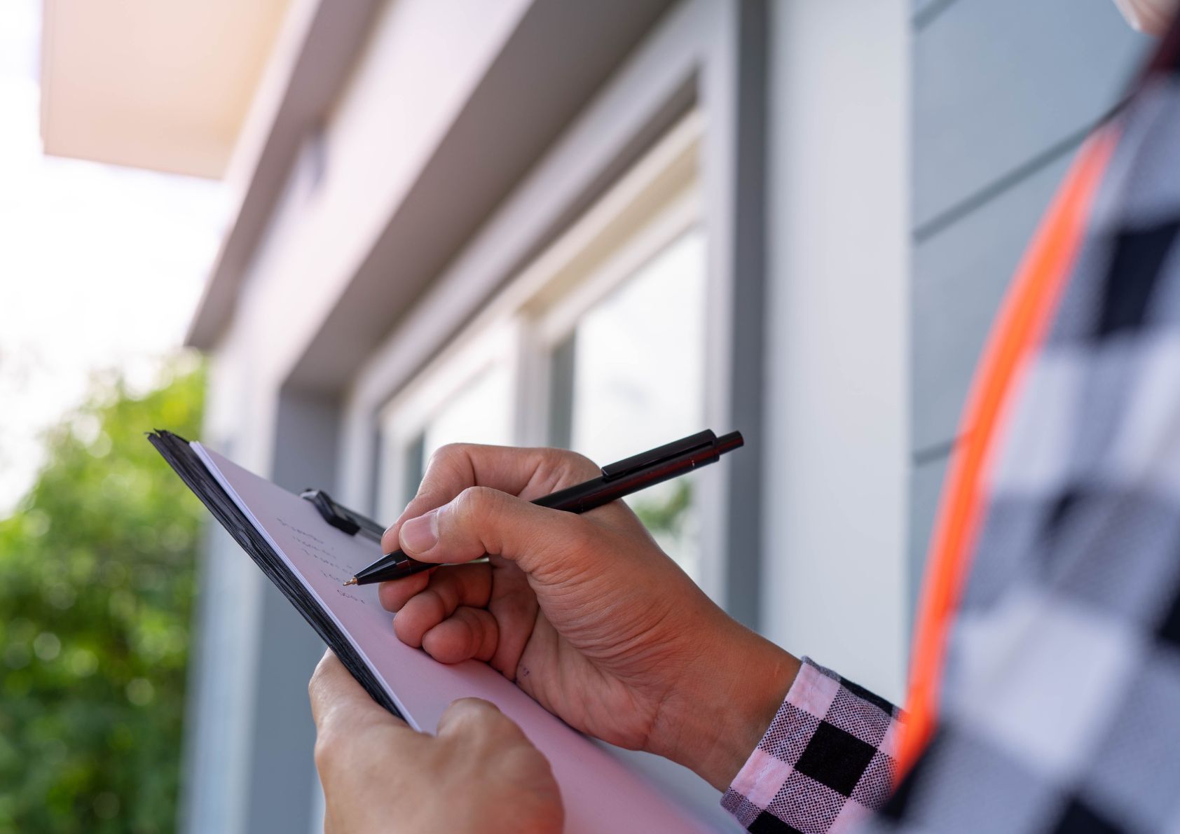 man with clip board inspecting house