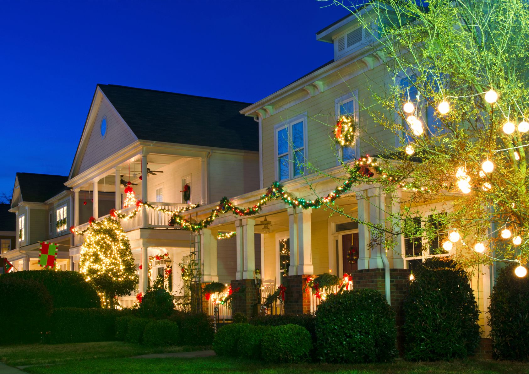 a row of homes decorated with lights and holiday decor. 